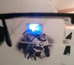 Blick durch die Brille. Die integrierte Kamera hat das schwarzweiße Motiv erkannt und zeigt ein farbiges 3D-Modell davon an. Das Bild wird von rechts auf das Glas projeziert.